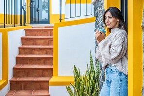 A staircase with yellow railings and a person holding a blue object. - Villa Piedade by Homie (Ponta do Sol)