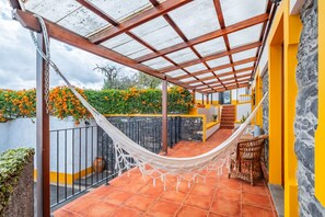 Un espace extérieur abrité comprenant un hamac, un escalier et un mur jaune.