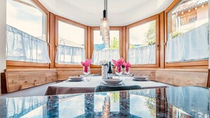 A dining area with a glass table, wooden benches, and a chandelier.