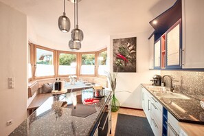 Una cocina moderna con una isla grande, luces colgantes y vistas al exterior.