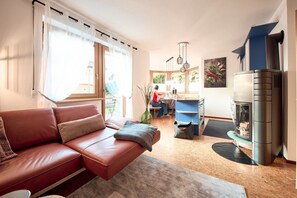 Una sala de estar moderna con un sofá de cuero, un comedor y un estufa de leña empotrada.
