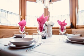Une table mise pour le repas, avec des assiettes, des verres et un vase rempli de fleurs.