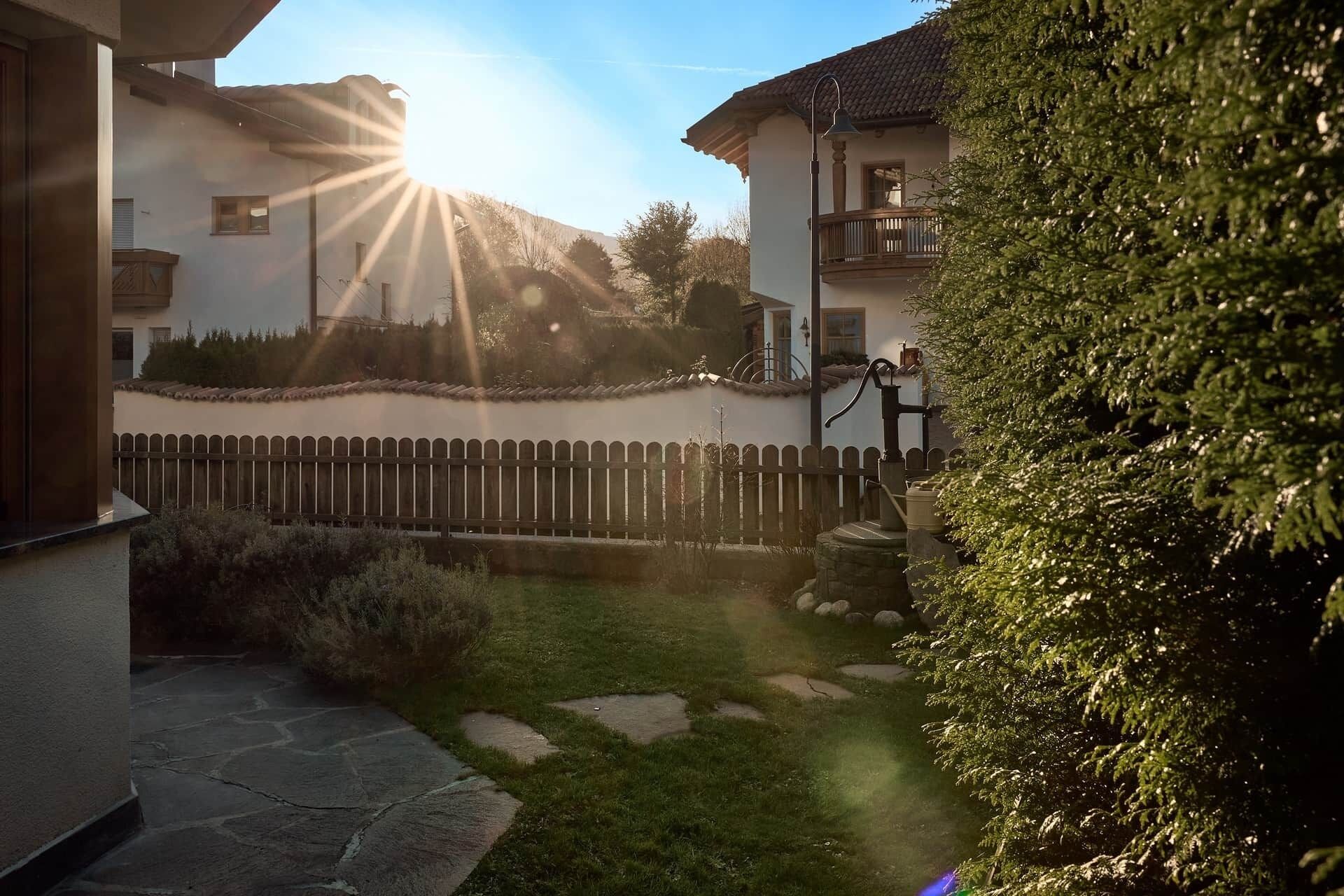 A courtyard with a stone pathway, a wooden fence, and a well-maintained lawn.