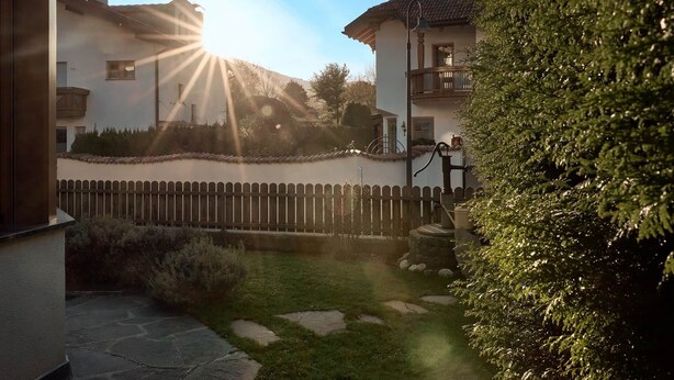A courtyard with a stone pathway, a wooden fence, and a well-maintained lawn.