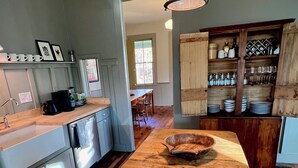 Une cuisine avec un plancher en bois, un îlot central et un luminaire suspendu.