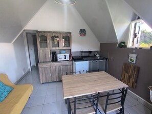 Eine kompakte Küche mit Essbereich, einer Mikrowelle, einer Kaffeemaschine und einer Uhr an der Wand.