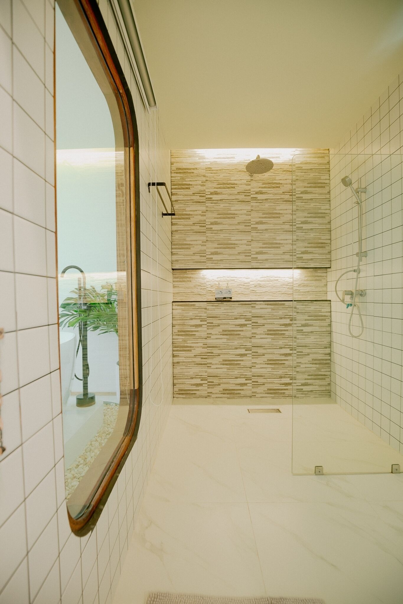 Un baño moderno con cabina de ducha de vidrio, un panel de pared de madera y suelo de baldosas.