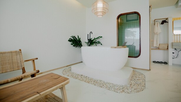A modern bathroom with a freestanding bathtub, a wooden chair, and a small table. - Fan Sea Resort Kohlarn (Koh Lan)