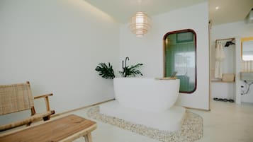 Relax in a serene space with a bathtub, wooden chair, and potted plant.