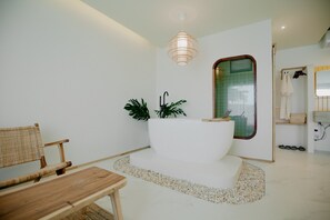 A modern bathroom with a freestanding bathtub, a wooden chair, and a small table. - Fan Sea Resort Kohlarn (Koh Lan)