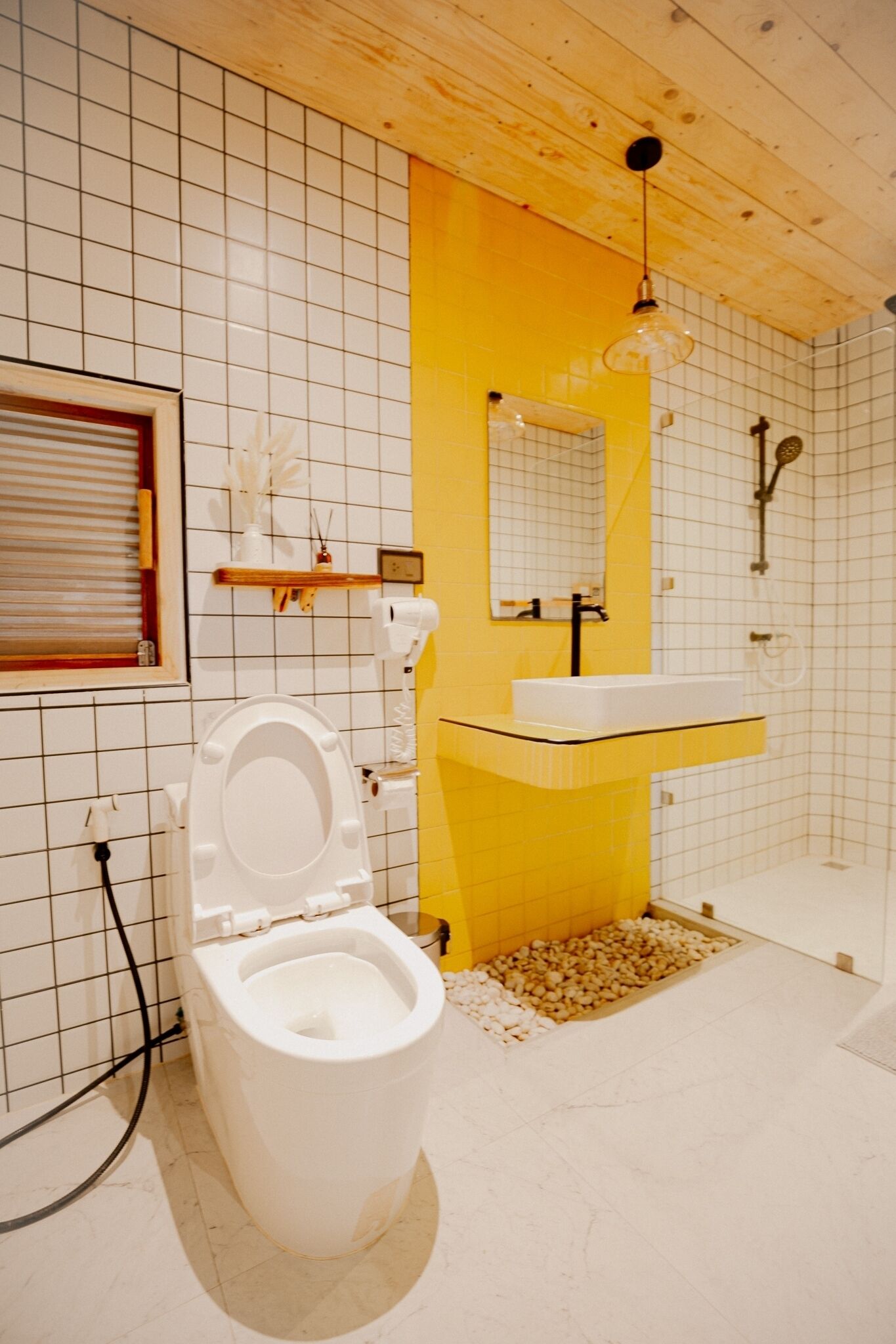 Et badeværelse med et hvidt toilet, en gulvbelagt vask og en bruser.
