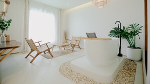 A modern living room with a white reception desk, wooden chairs, a small table, and a potted plant. - Fan Sea Resort Kohlarn (Koh Lan)