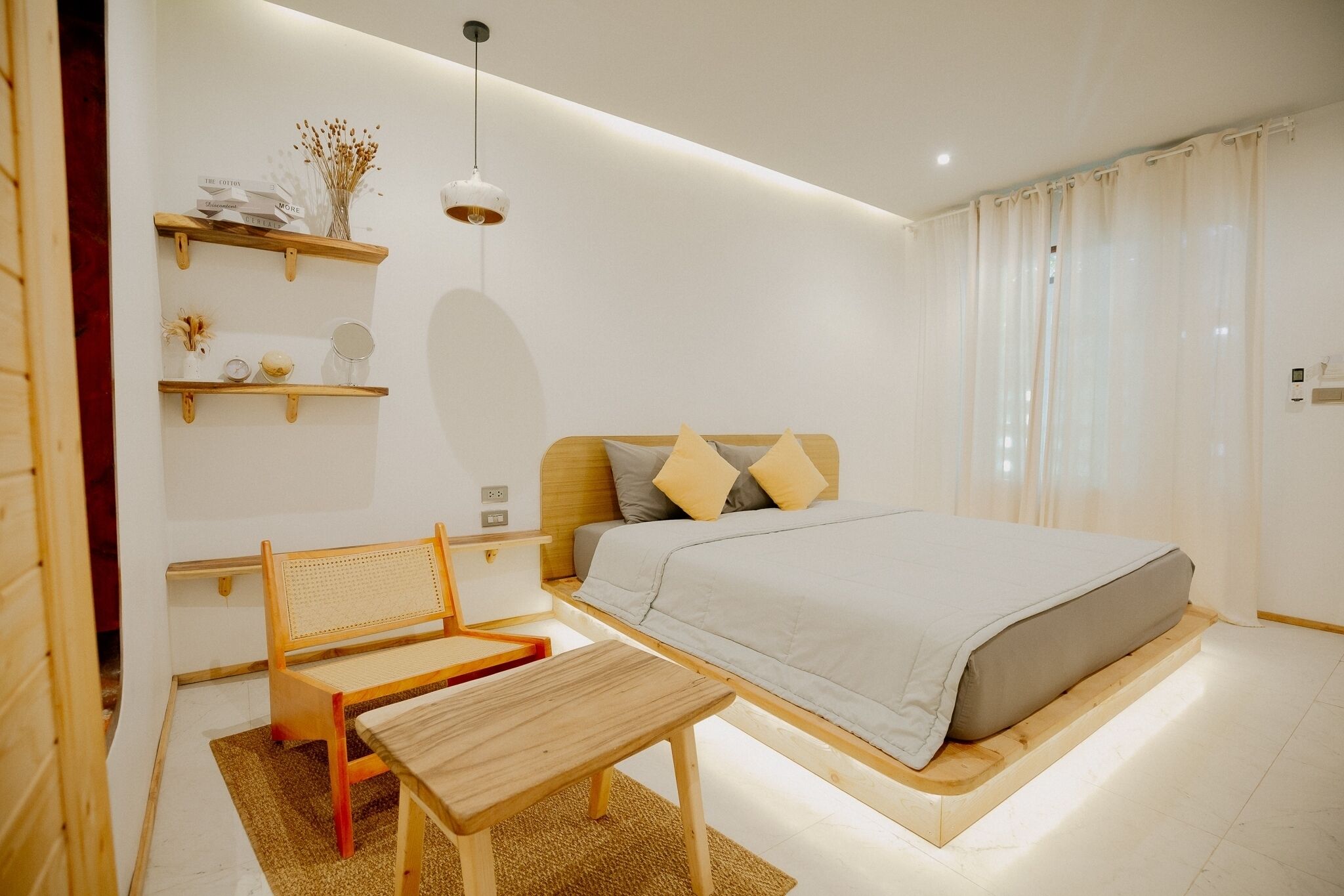 Une chambre moderne comprenant un lit, une table de chevet, une chaise et des étagères ornées d’objets décoratifs.