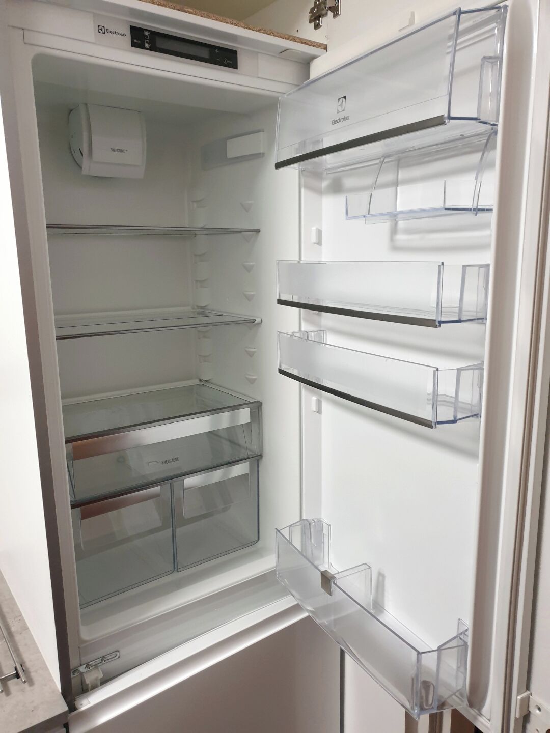 An open refrigerator with multiple transparent shelves and a freezer compartment.