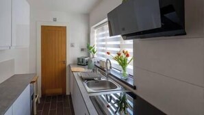 A compact kitchen with a wooden door, a window with a view, a sink, and a stove.
