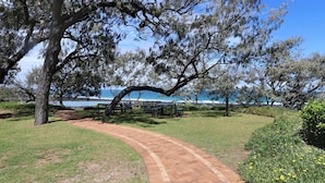 A paved pathway leading to a bench area with a view of the ocean.