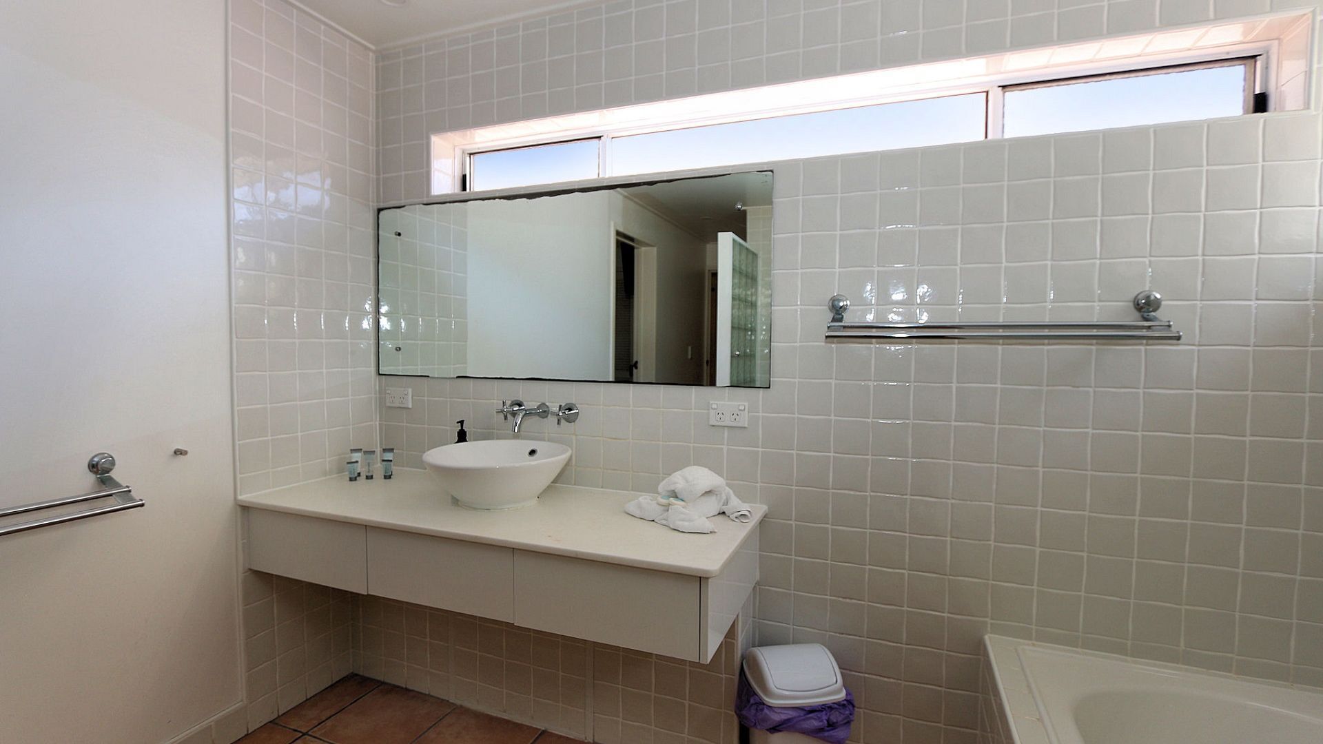 A bathroom with a white sink, mirror, and a small window above the mirror.