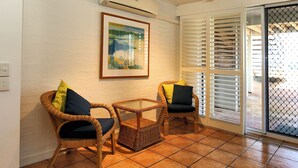 A room with wicker chairs, a glass table, and a framed painting on the wall.