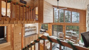 L’intérieur d’un chalet en bois comprend un coin repas, une cuisine et un balcon aménagé avec des sièges.