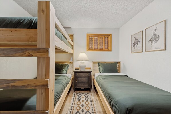 A dorm-style room with bunk beds, a nightstand with a lamp, and two framed pictures on the wall. - Big Mountain Home with Private Spa - 4 bedroom/3ba with Views (Whitefish)
