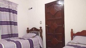 Una habitación con dos camas individuales, cada una con cabecero de madera y cubrecama a rayas.