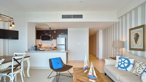 A modern living room with a sofa, coffee table, and chairs. There is a kitchen area with a microwave and refrigerator in the background. - Marvelous Ocean Views, Harmony 6FLR Apt at Las Olas Metro Country Club - Unit #1 (Juan Dolio Beach)