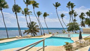 A pool area with palm trees and a view of the ocean. - Marvelous Ocean Views, Harmony 6FLR Apt at Las Olas Metro Country Club - Unit #1 (Juan Dolio Beach)