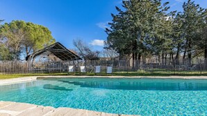 Una piscina limpida con una recinzione in legno e un padiglione coperto.