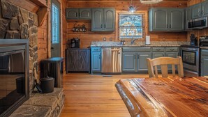 Een houten chalet interieur met een stenen open haard, granieten aanrechtbladen en een eettafel.