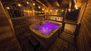 Een hottub op een houten terras, met lichtjes en een houten omheining.