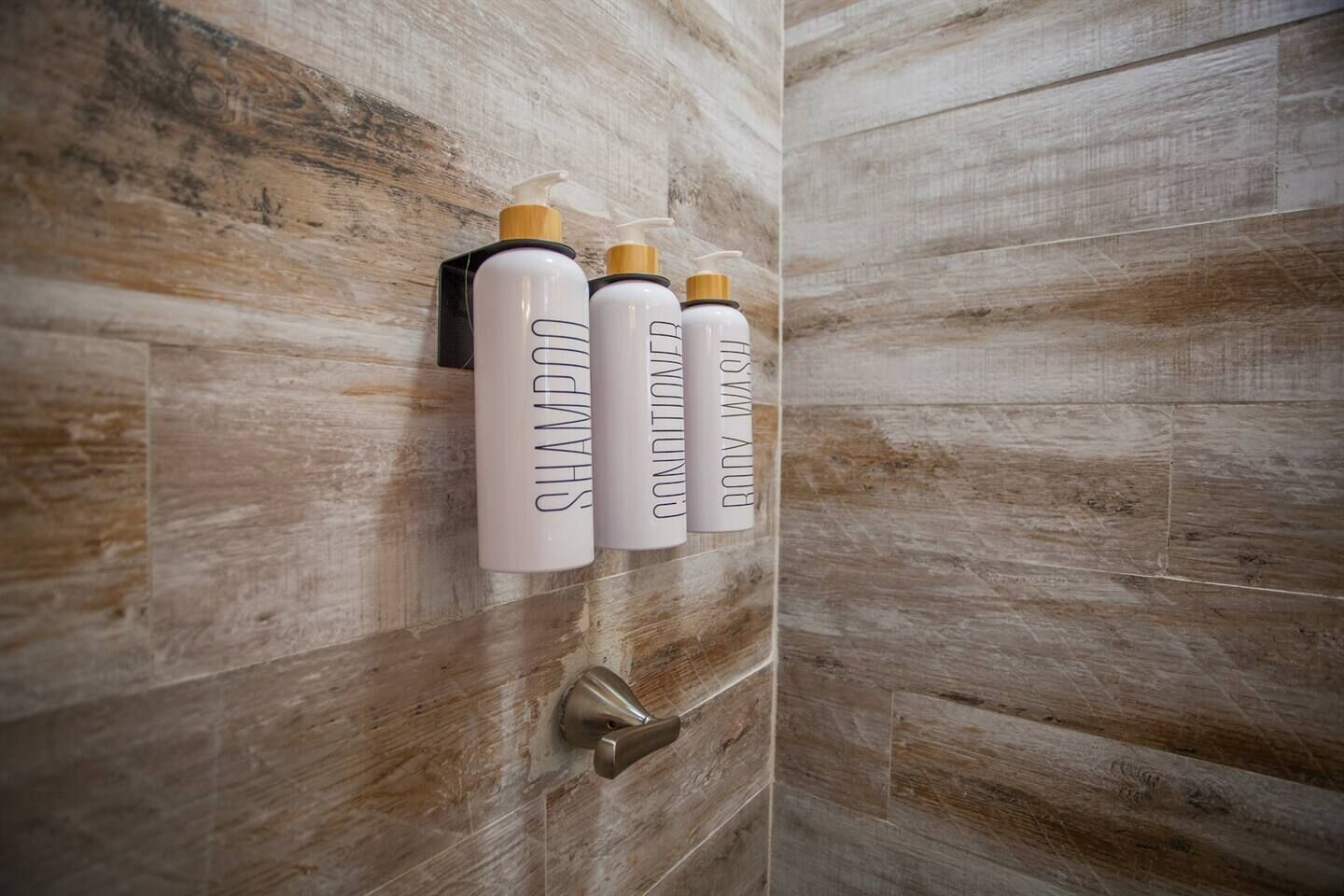 Tres botellas de champú y acondicionador sobre una pared de madera.