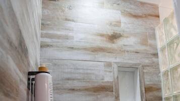 A shower with a wooden wall, a small window, and a showerhead.