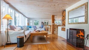 Een knusse woonkamer met een open haard, houten vloeren en een eethoek.