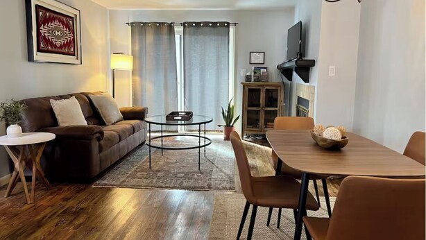 A living room with a sofa, coffee table, dining table, chairs, and a chandelier.