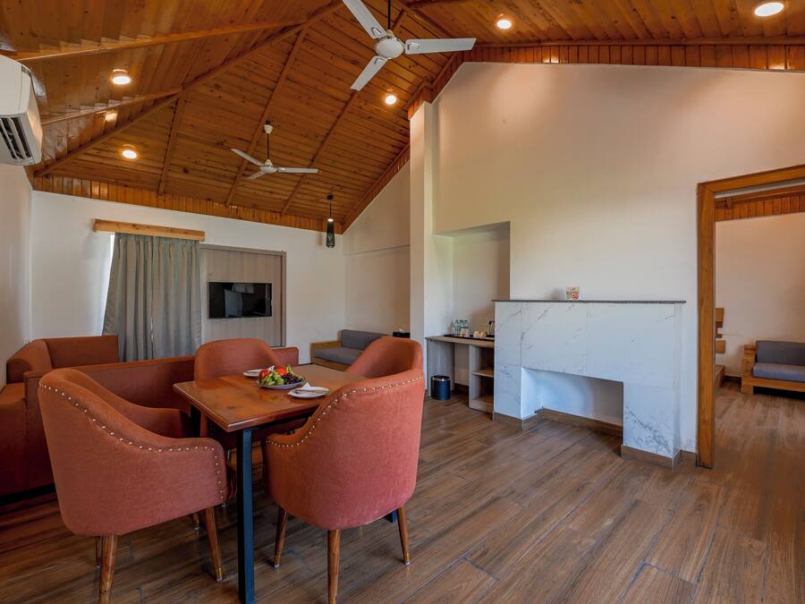 A spacious room with a wooden ceiling, a dining area with two chairs and a table, a kitchen area, and a seating area with a couch.