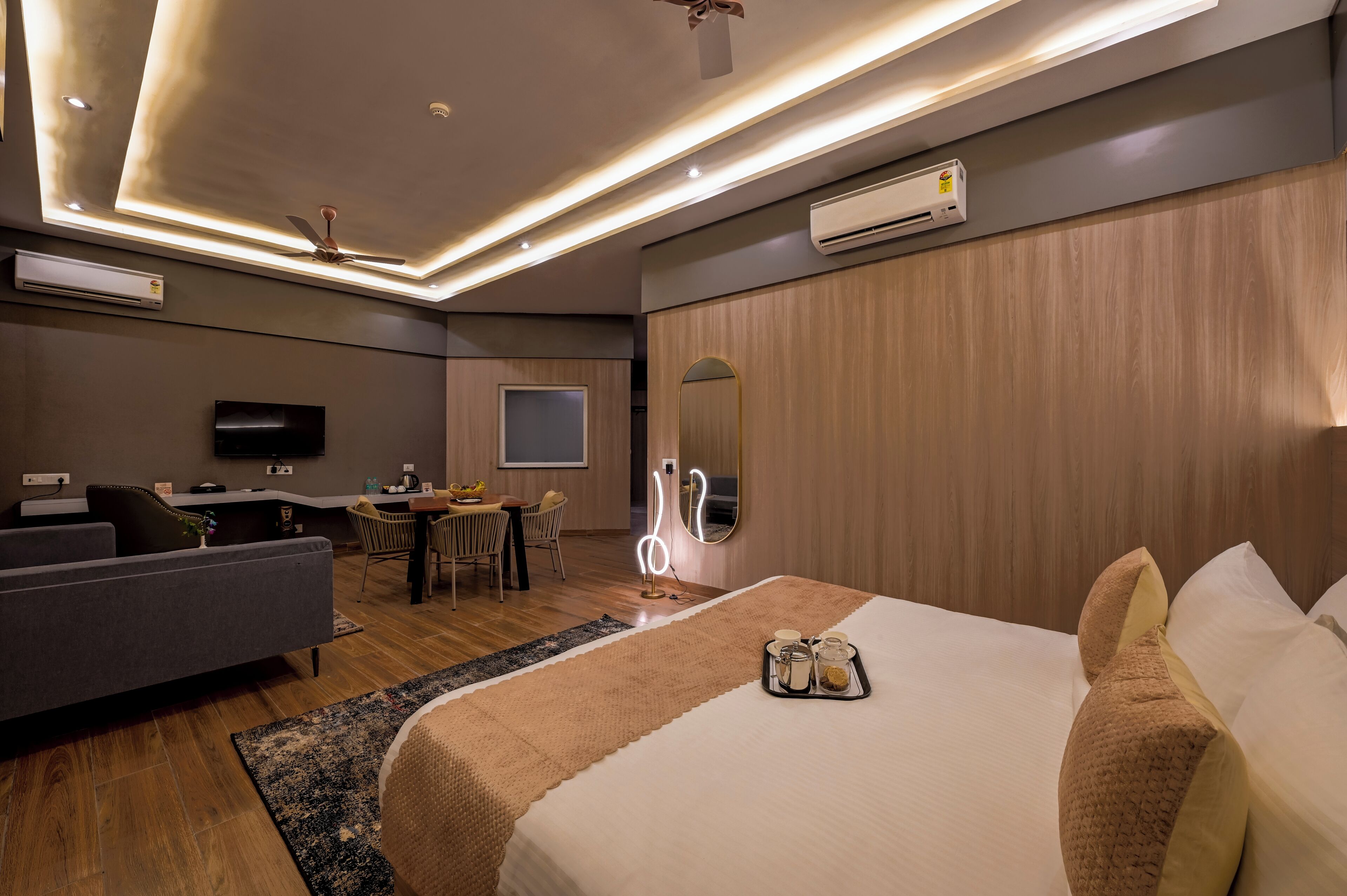 Una habitación de hotel moderna con una cama, un sofá, una zona de comedor y un televisor.