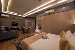 Una habitación de hotel moderna con una cama, un sofá, una zona de comedor y un televisor.