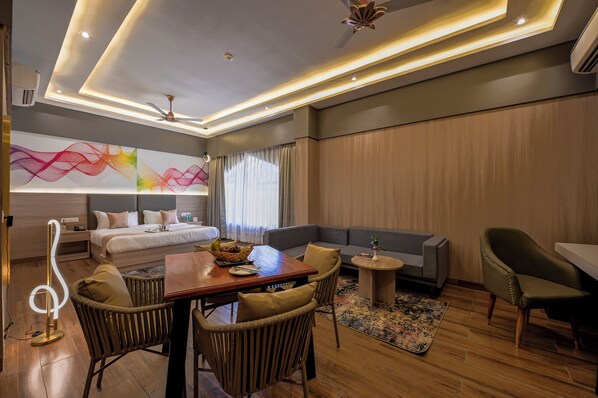 A modern hotel room with a bed, sofa, dining table, and chairs. - Corbett Platinum Heritage (Ramnagar)