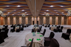 Un salón de conferencias con mesas redondas, sillas negras y un diseño moderno de techo.