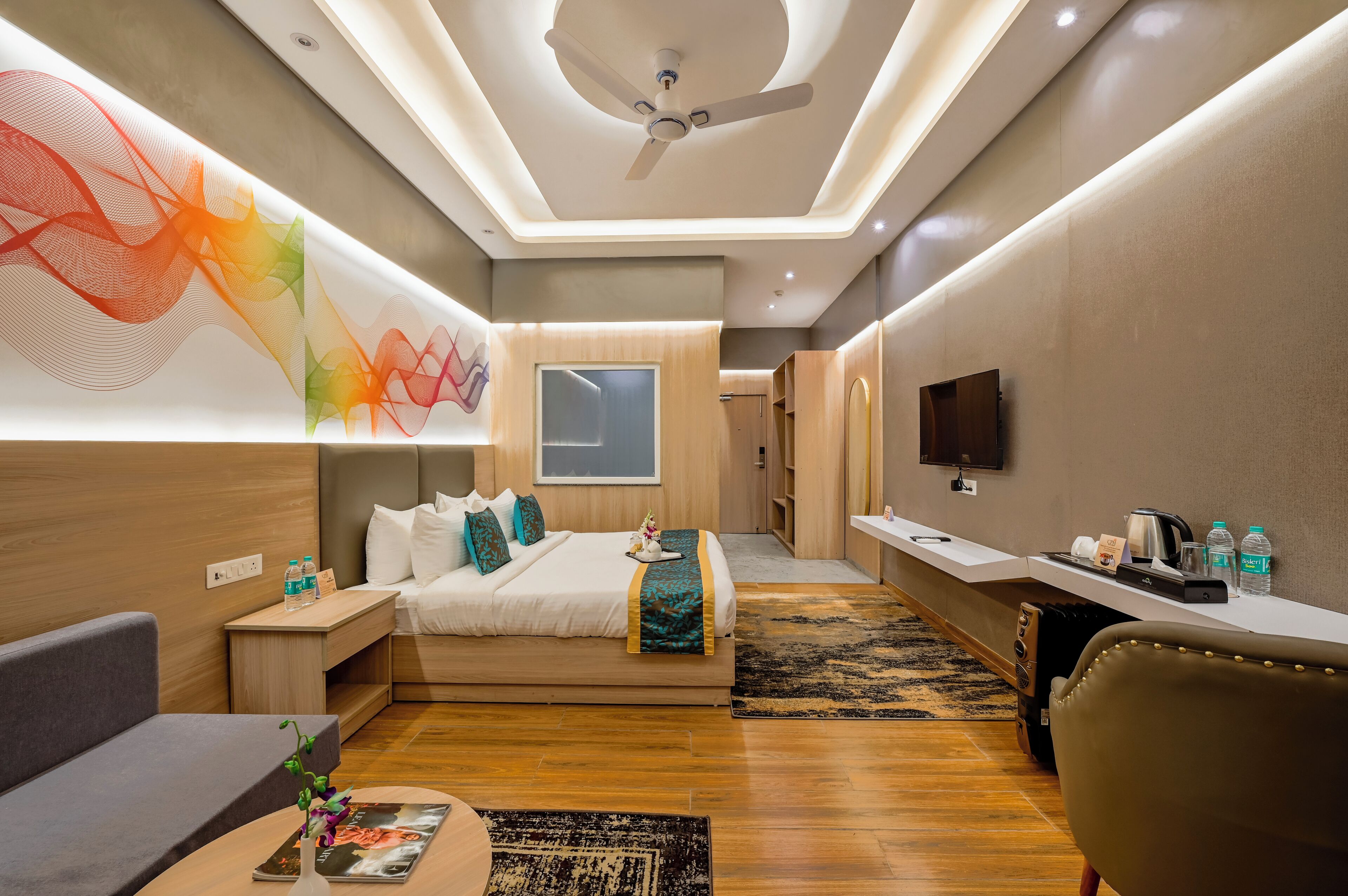 Una habitación de hotel moderna con cama, mesita de noche, escritorio, silla y televisor.