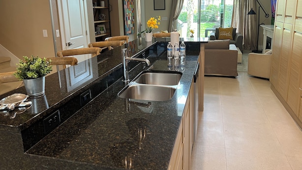 Una cocina moderna con encimera de granito, pileta de acero inoxidable e iluminación colgante.