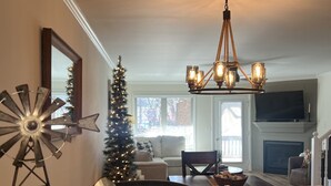 A cozy living room with a fireplace, a Christmas tree, and a 'WELCOME' sign on the counter.