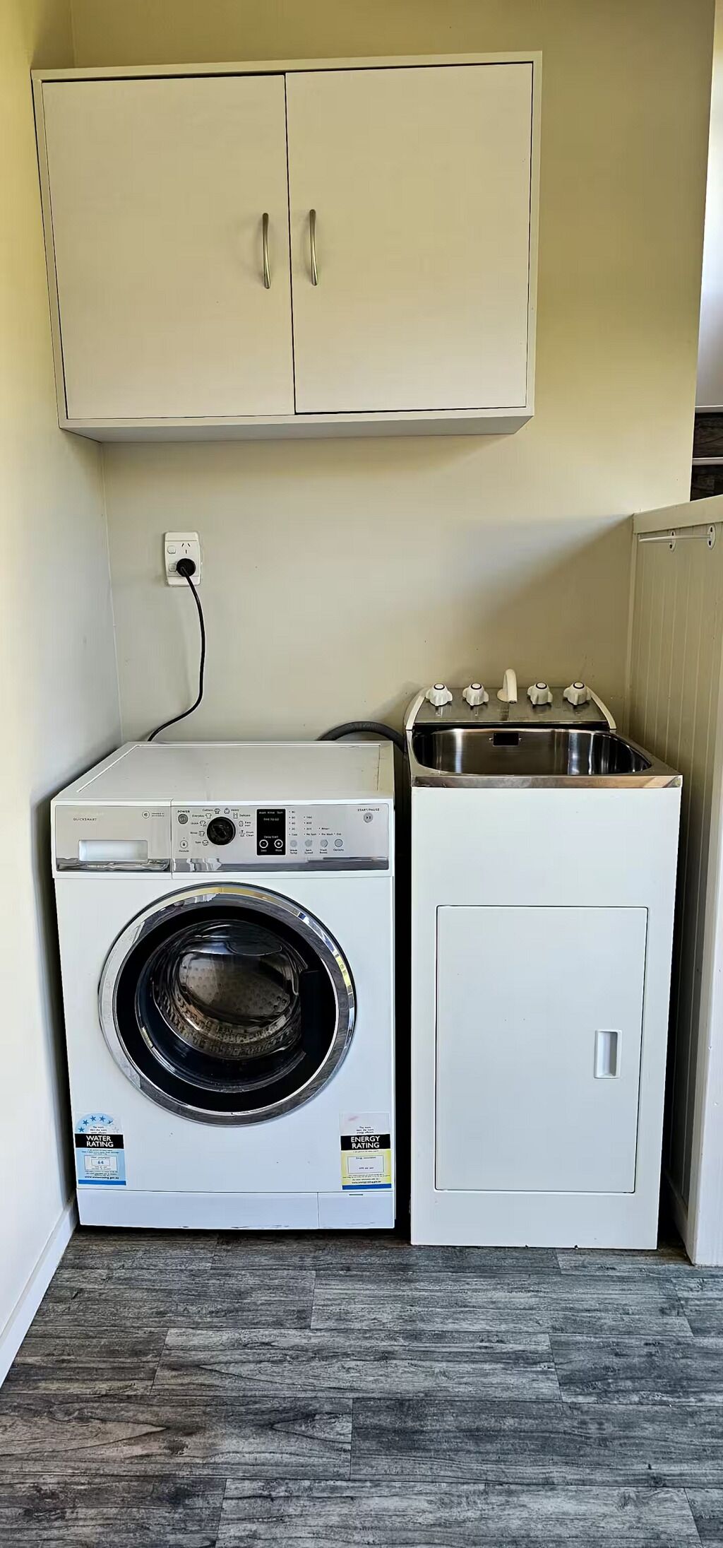 A compact laundry room with a front-loading washing machine and a stacked dryer.