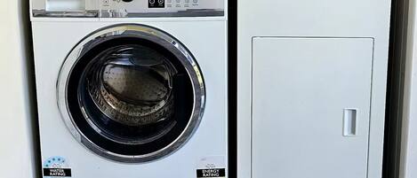 A compact laundry room with a front-loading washing machine and a stacked dryer.