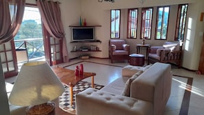 A spacious living room with a sofa, a television, and a dining area with a table and chairs. - House in Guapimirim/Caneca Fina - Gated community (Guapimirim)