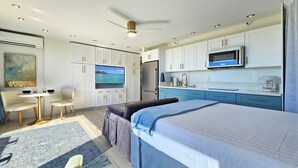 A modern bedroom with a large bed, a desk, and a television.