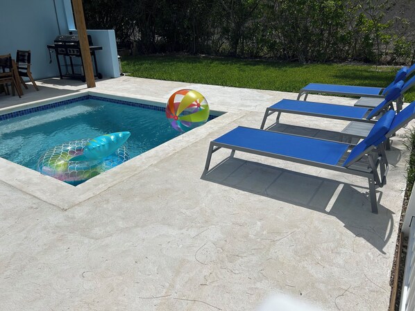 A swimming pool with blue lounge chairs and a colorful beach ball.