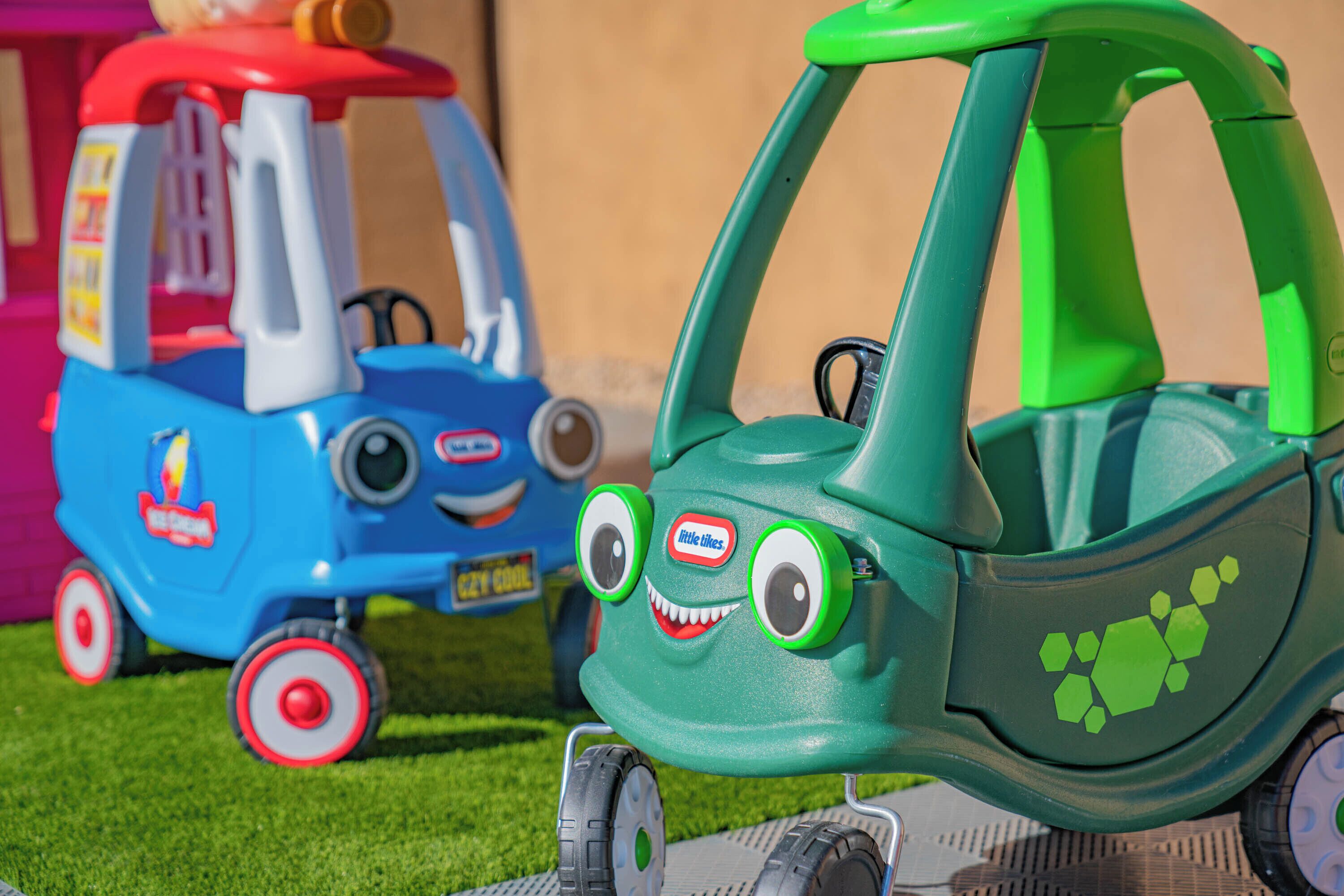 Twee speelgoedauto's, één blauw en één groen, met wielen en stuur.