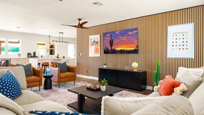 A modern living room with a sofa, armchairs, a coffee table, and a TV mounted on a wooden wall. - Scottsdale Retreat | Pool & Spa | GameRoom (Scottsdale)