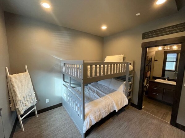 A bedroom with a bunk bed, a small chair, a vanity with a mirror, and a staircase. - Charming 2-bedroom shop house on the beautiful Columbia River (Entiat)